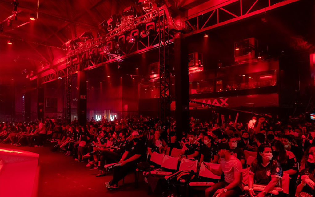 Plateia em frente ao palco com luzes vermelhas da MAX Arena, uma das principais Arenas de e-sports do Brasil.