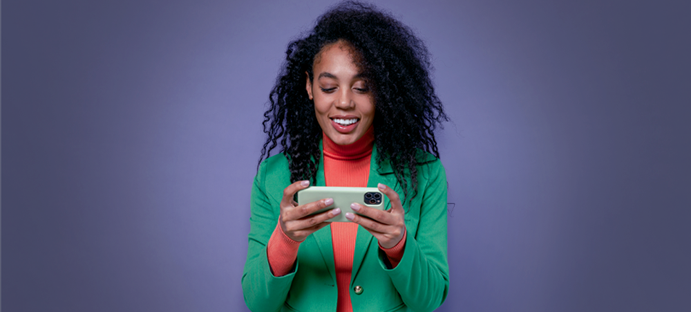 Mulher com smartphone na horizontal representando a leitura do glossário gamer.