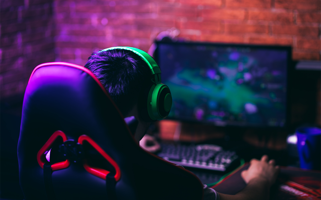Pessoa jogando online em cadeira gamer usando headset.