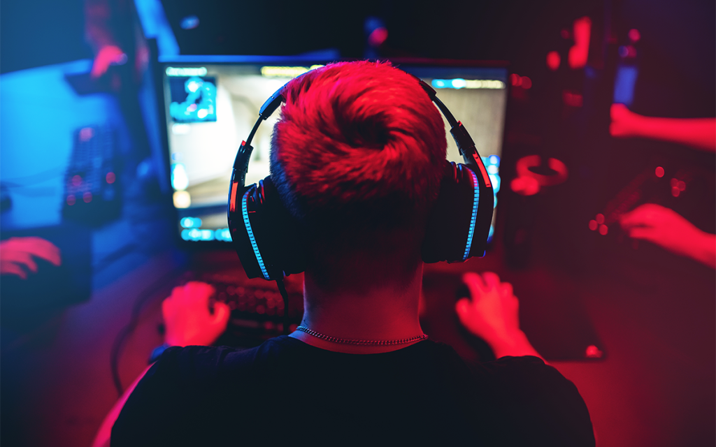 pessoa de costas jogando game em computador usando headset