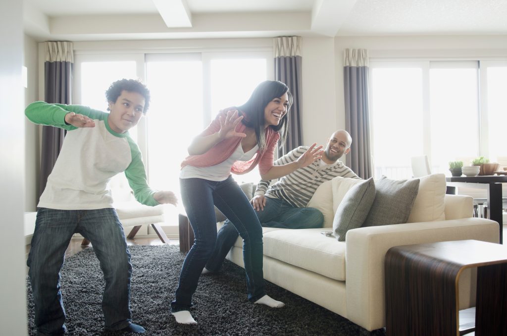 família se divertindo com video-game com sensor de movimentos em casa 