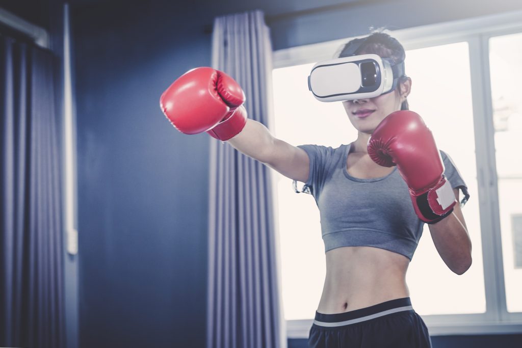 mulher usando óculos de realidade aumentada praticando exercícios, algo comum segundo a PGB quanto ao hábito de consumo dos gamers