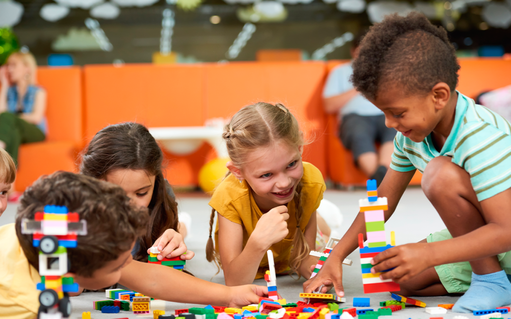grupo de crianças montando blocos de montar sorrindo e aprendendo com gamificação na educação
