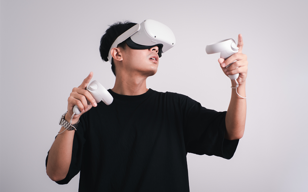 homem em pé jogando video-game com óculos de realidade virtual e dois controles