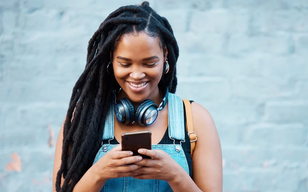 jovem sorrindo mexendo no celular com headset no pescoço