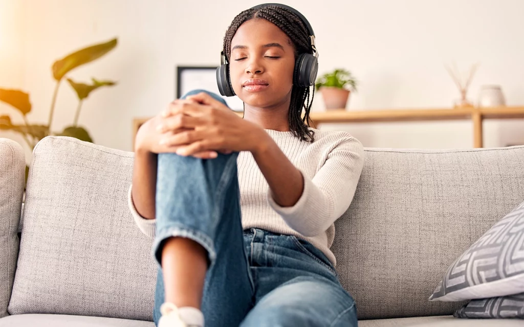 jovem relaxada ouvindo música no headset de olhos fechados no sofá de casa